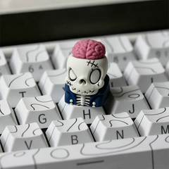 OZO Keyboards artisan keycap featuring a cartoon skull with an exposed pink brain and blue jacket on a white keyboard