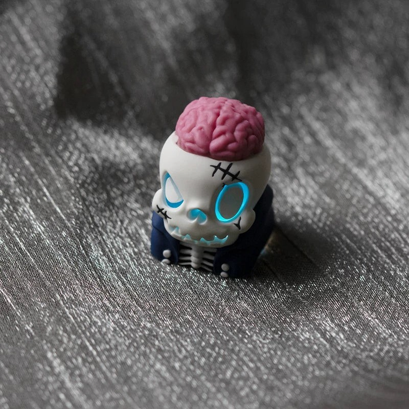 OZO Keyboards artisan keycap featuring a white skull with an exposed pink brain and glowing blue eyes