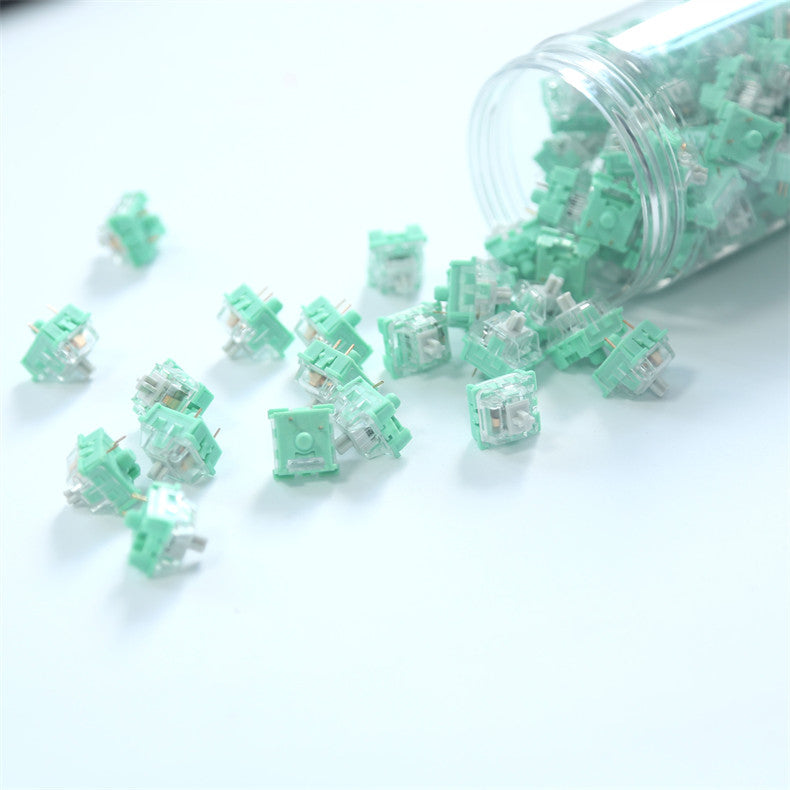 Mint green mechanical switches spilling out of a clear container on a white background