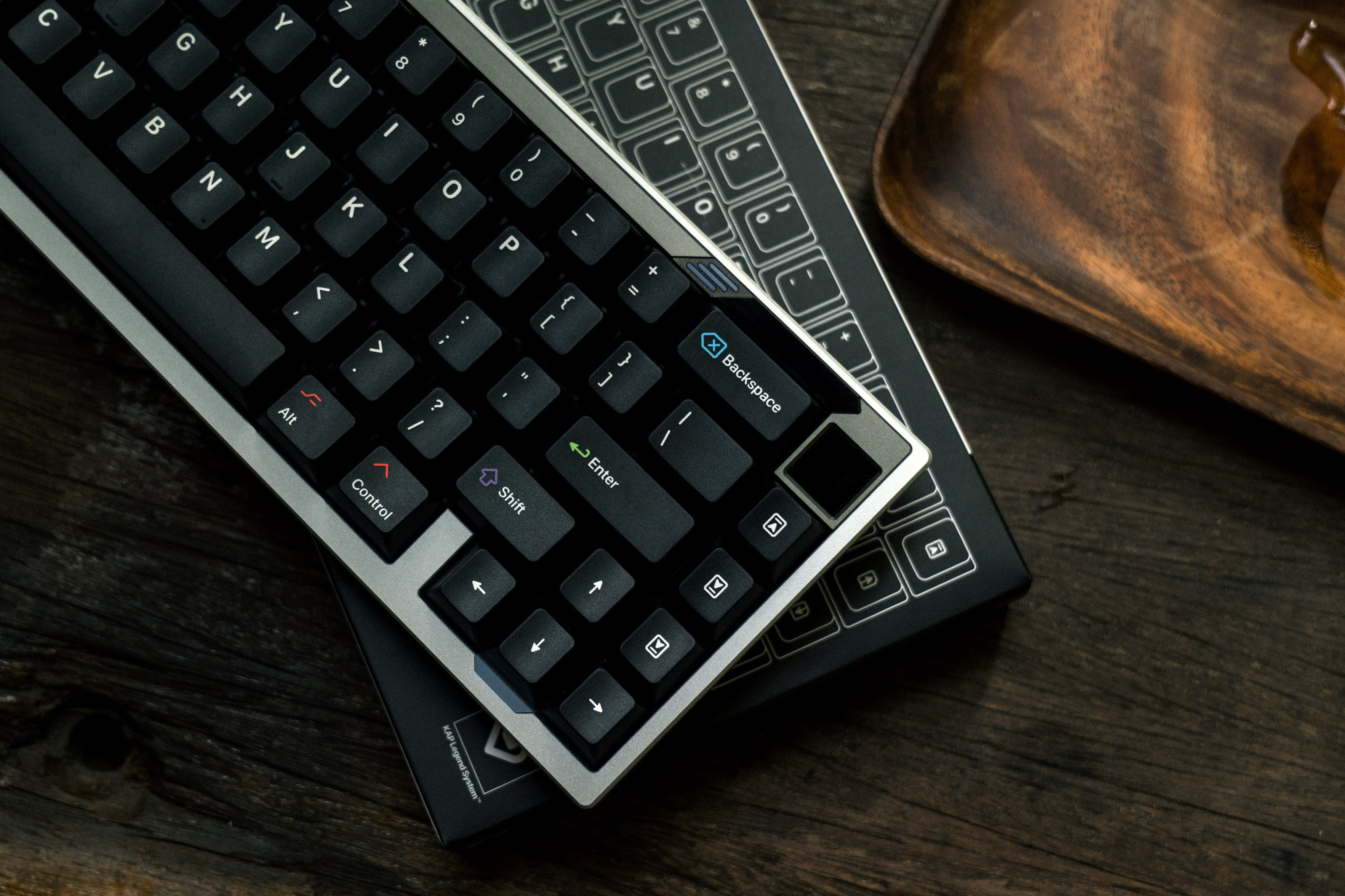 Close up shot of a Paper65 keyboard in titan silver case colour on a wooden surface.