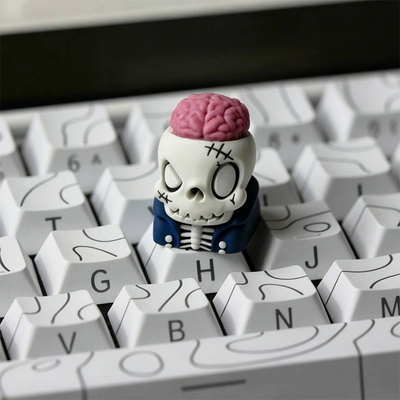 OZO Keyboards artisan keycap featuring a cartoon skull with an exposed pink brain and blue jacket on a white keyboard