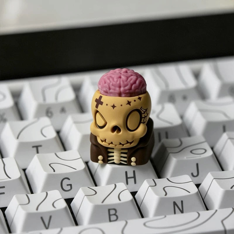 OZO Keyboards artisan keycap featuring a beige skull with an exposed pink brain and brown jacket on a white keyboard