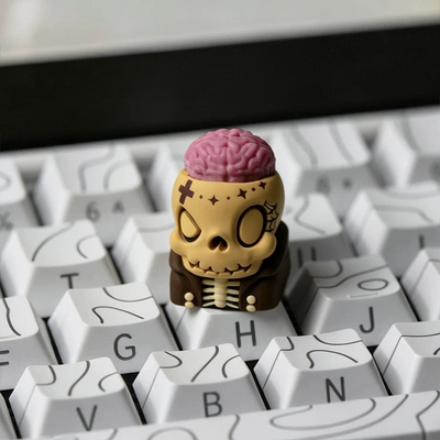 OZO Keyboards artisan keycap featuring a beige skull with an exposed pink brain and brown jacket on a white keyboard