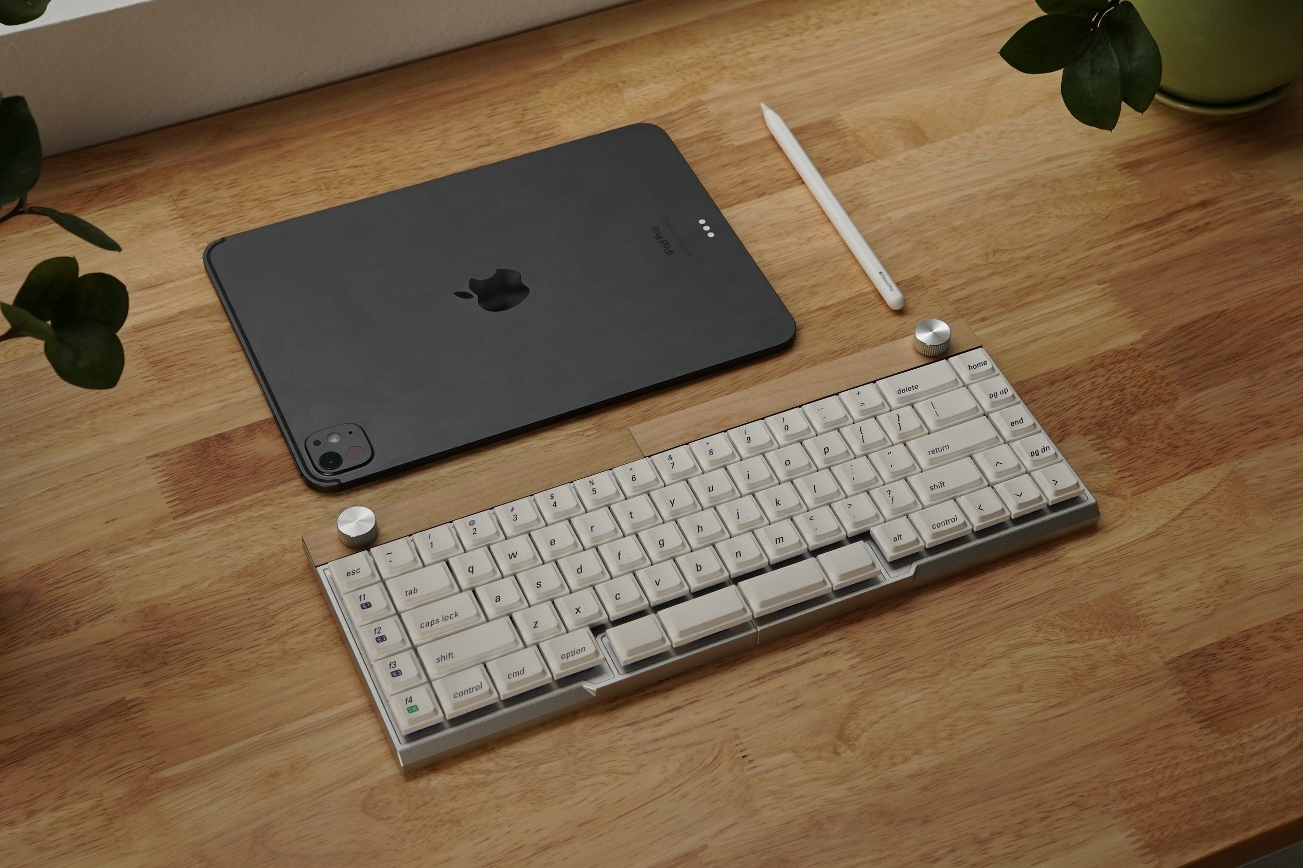 Grey Jiffy75 keyboard and tablet on a wooden desk with a plant in the background