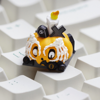 OZO Keyboards artisan keycap featuring a spooky orange pumpkin with skeleton hands, a tombstone, and a candle.