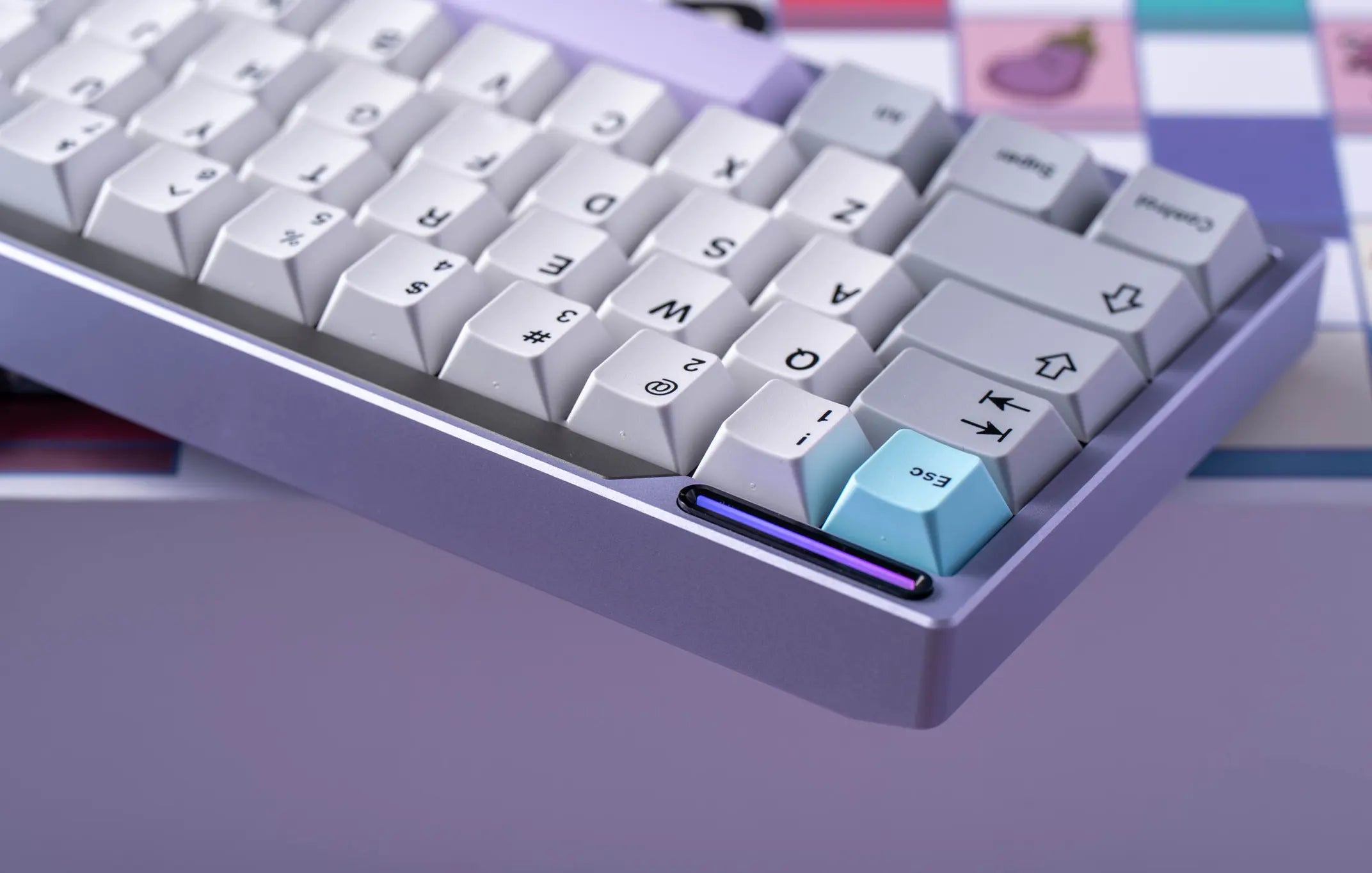Close-up of a mechanical keyboard with a focus on the RGB slim light strip in oval frame in the top left corner of the case.